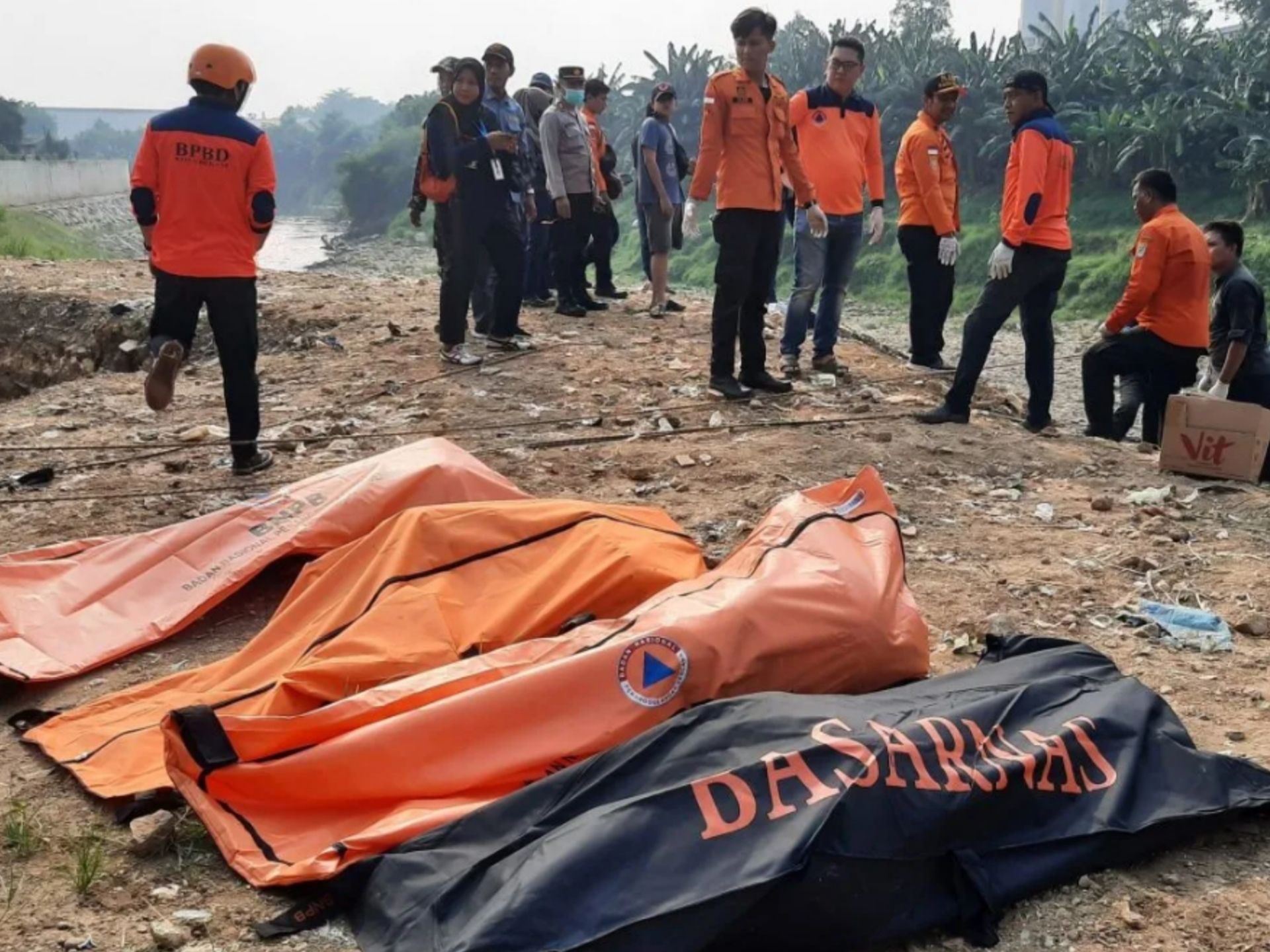 Sejumlah petugas BPBD Kota Bekasi dan polisi berdiri dengan latar depan kantong-kantong berisi tujuh jenazah laki laki yang ditemukan mengambang di Kali Bekasi, Pondok Gede Permai, Jatiasih, Kota Bekasi, Minggu (22/9/2024). Kepolisian masih menyelidiki penyebab kematian tujuh orang tersebut