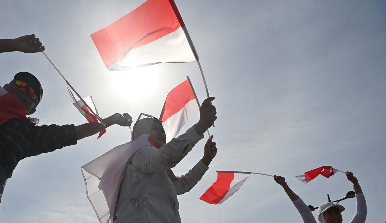 Sejumlah warga mengibarkan bendera Indonesia.