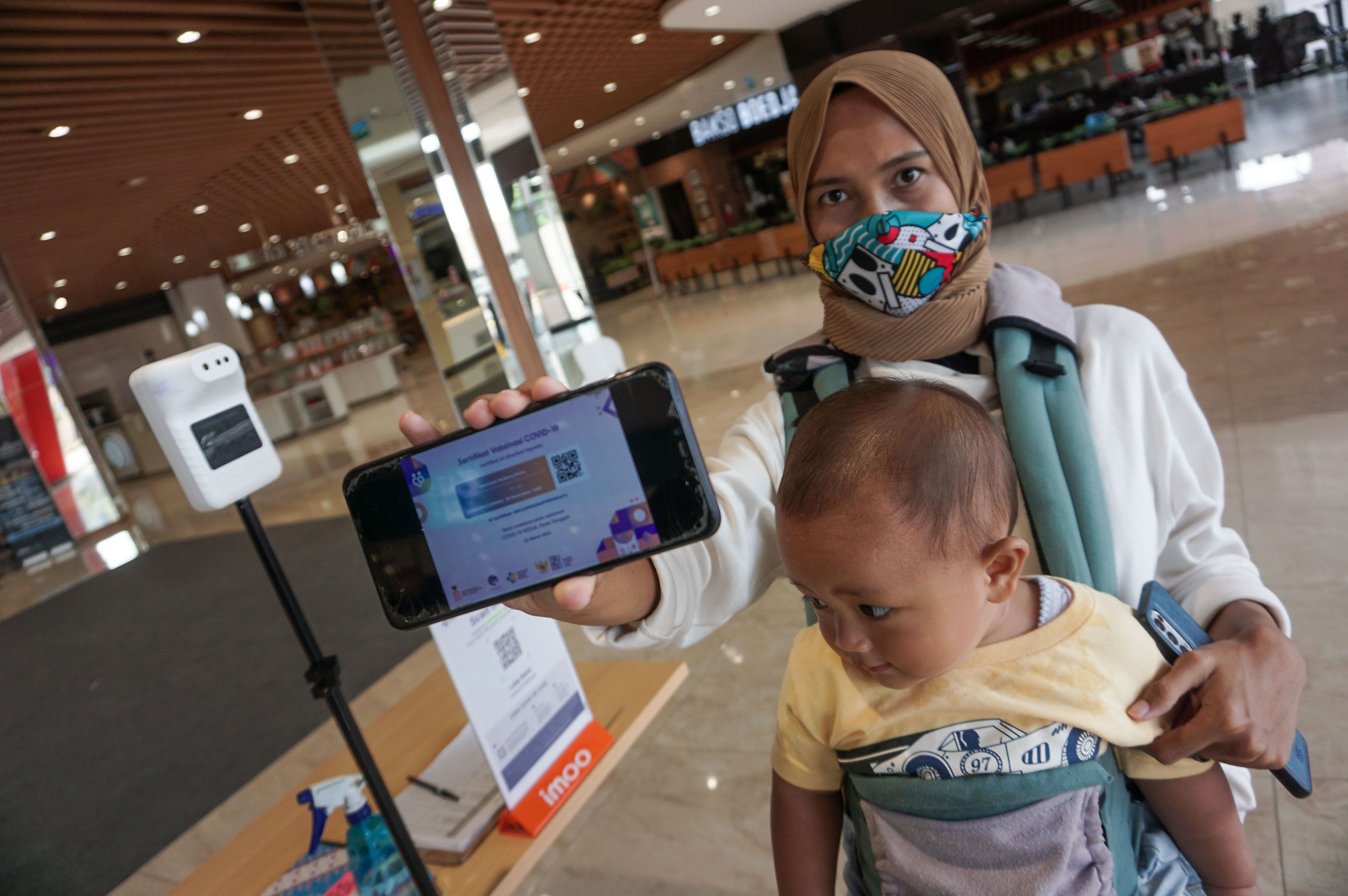 Pengunjung menunjukkan sertifikat vaksin Covid-19 usai memindai QR code melalui aplikasi PeduliLindungi di salah satu pusat perbelanjaan