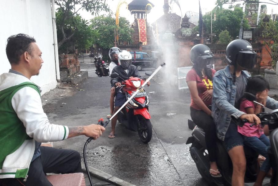 Petugas melakukan penyemprotan disinfektan kepada pengunjung Pasar Badung Bali untuk mengantisipasi penyebaran Covid-19.*/