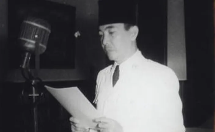 Presiden Sukarno sedang berpidato di depan podium dalam sebuah acara.