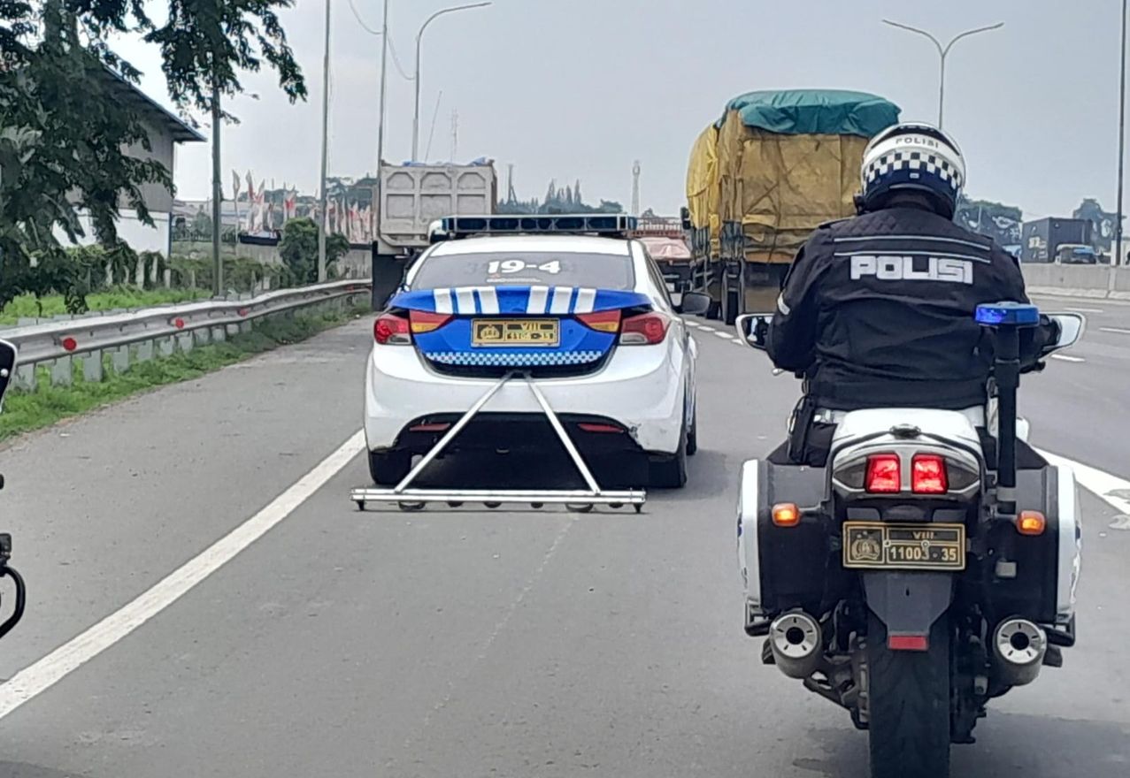 Mobil patroli yang diberi tambahan alat penyapu ranjau paku sedang dioperasikan di jalan arteri Karawang. 