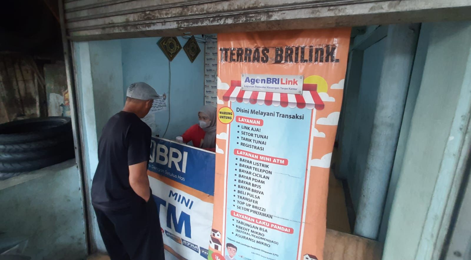 Ahmad (kiri), pedagang sayur, yang merasa aman bertransaksi di Terras BRILink, Cicaheum, Bandung.
