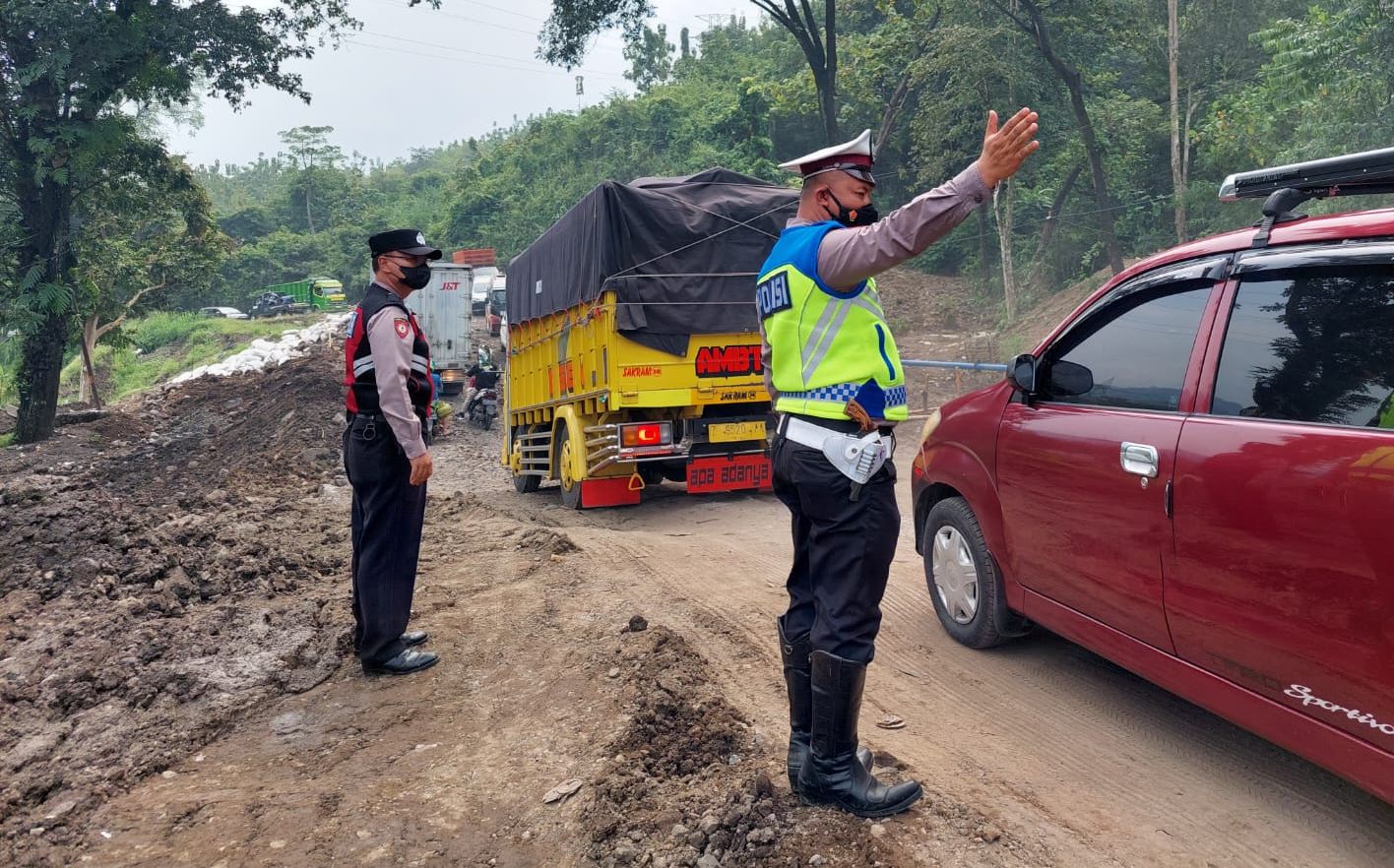 Personel Satlantas Polres Sumedang melakukan pengaturan lalu lintas di lokasi Jalan Raya Sumedang-Cirebon yang amblas di wilayah Cireki, Kecamatan Tomo, Sumedang. Polisi mengimbau pengendara melalui jalur alternatif.