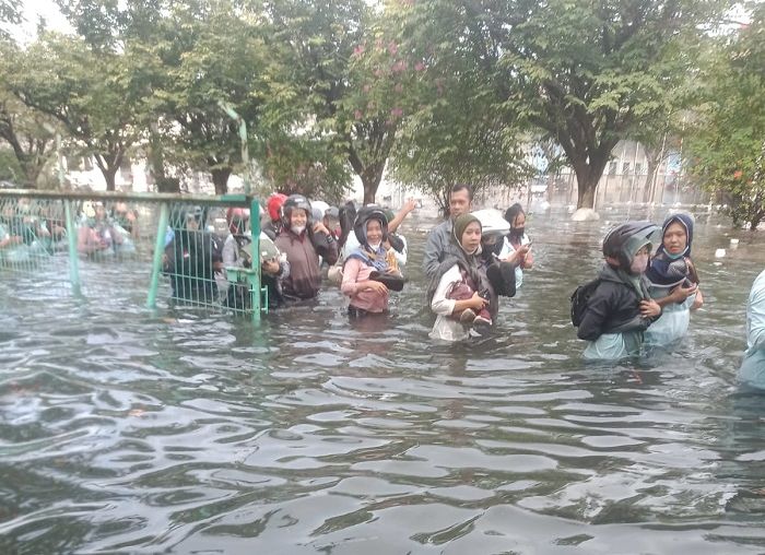 Para pekerja pabrik berusaha menyeberang banjir. 