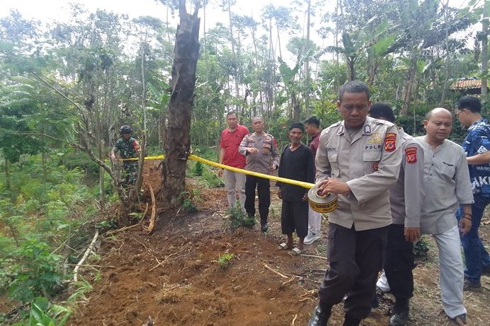 Polisi sedang memasang police line di lokasi keberadaan jamur yang diduga penyebab keracunan di Dusun Tugu, Desa Tugumulya, Kecamatan Darma, Kabupaten Kuningan pada Selasa, 21 November 2023.
