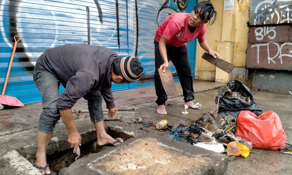 WARGA Beji, Depok, turun tangan membersihkan sampah yang menyumbat di gorong-gorong. Rabu 1 Januari 2020.*