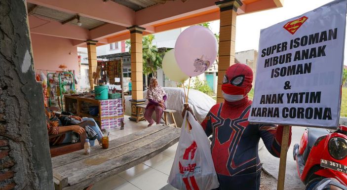Agus Widanarko (40), mengenakan kostum Spiderman, membawa spanduk bertuliskan