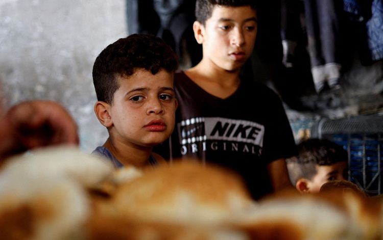 Seorang anak Palestina melihat roti yang dipanggang di oven kayu bakar, di tengah kekurangan bahan bakar dan listrik, saat konflik antara Hamas dan Israel berlanjut, di Khan Younis di selatan Jalur Gaza, 16 Oktober 2023.