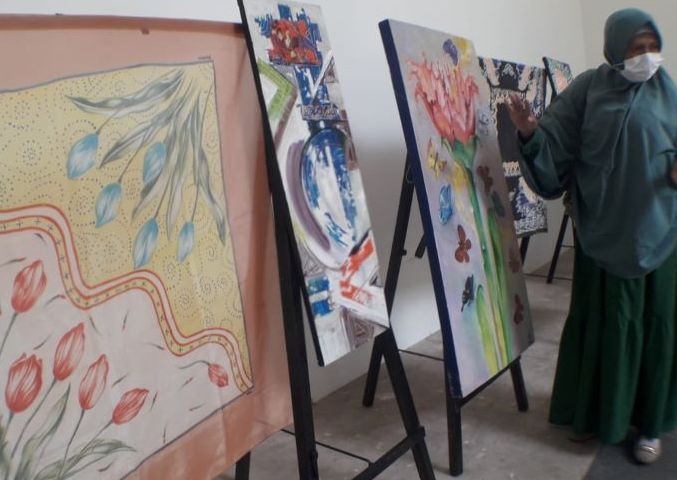 Seorang pengunjung tengah menyaksikan karya lukisan pada Pameran 40 Karya Pelukis SOS Babakan Siliwangi dalam rangka memperingati Hari Batik Nasional 2021.