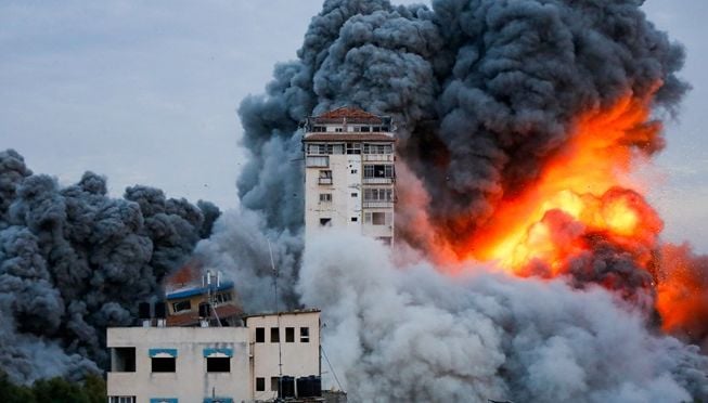 Asap dan nyala api berkobar setelah pasukan Israel menyerang sebuah menara pencakar langit di Kota Gaza, 7 Oktober 2023