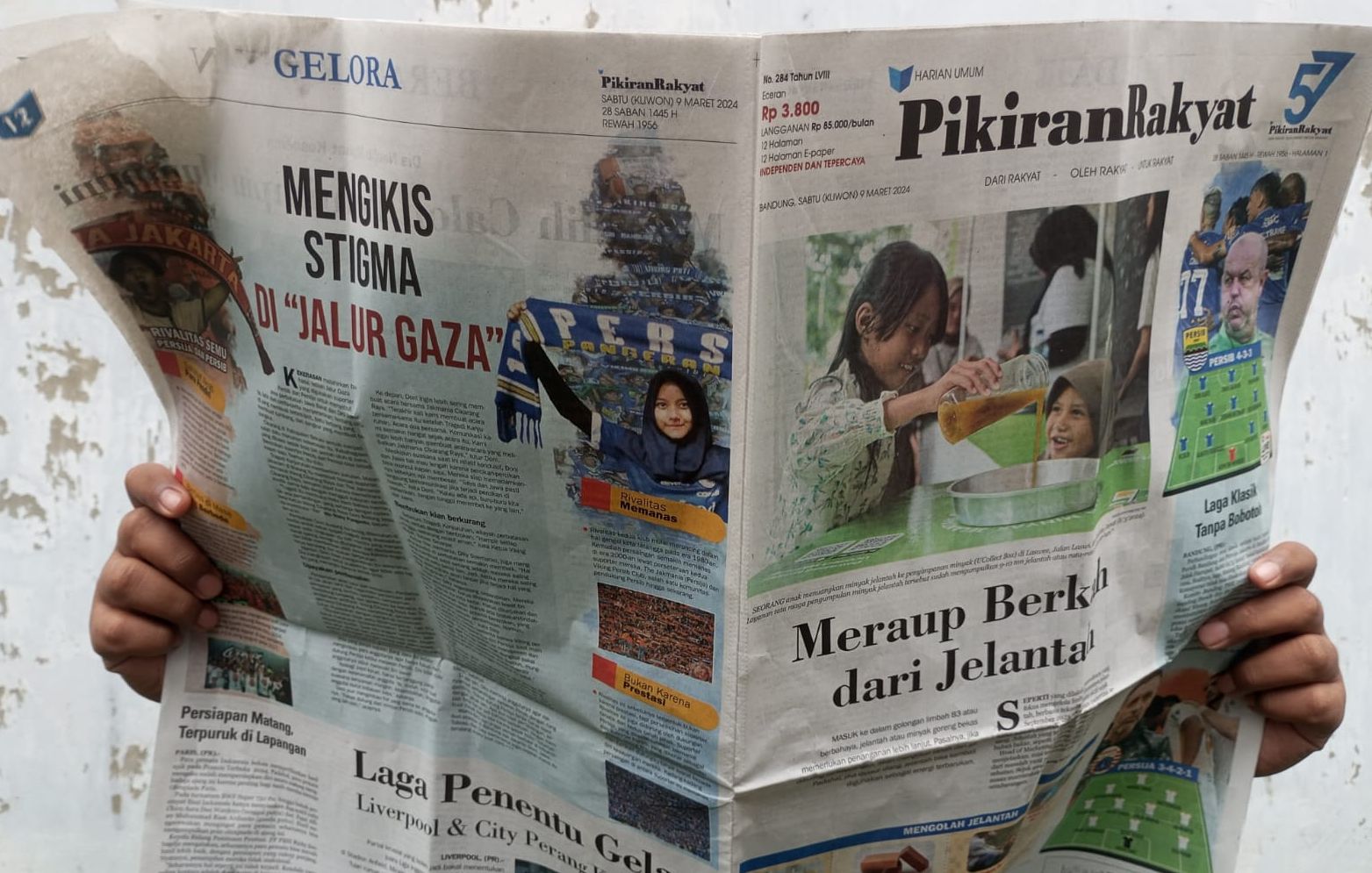 Ilham, seorang pembaca koran Pikiran Rakyat sedang membaca berita di Jalan Asia Afrika, Bandung, Jawa Barat, Sabtu, 9 Maret 2024.