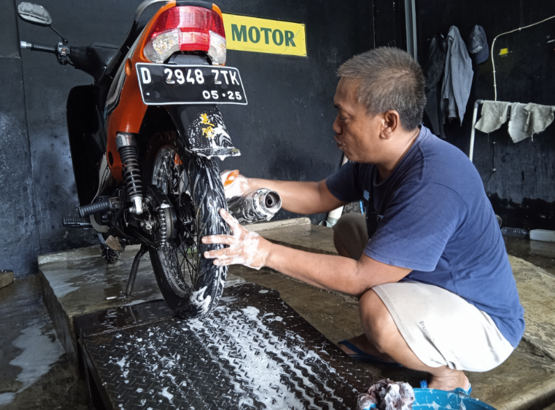 Iyan (48), tukang cuci sepeda motor di Jalan Raya Soreang Banjaran, Kabupaten Bandung, bisa menangani 100 unit sepeda motor selama Ramadhan menjelang lebaran.