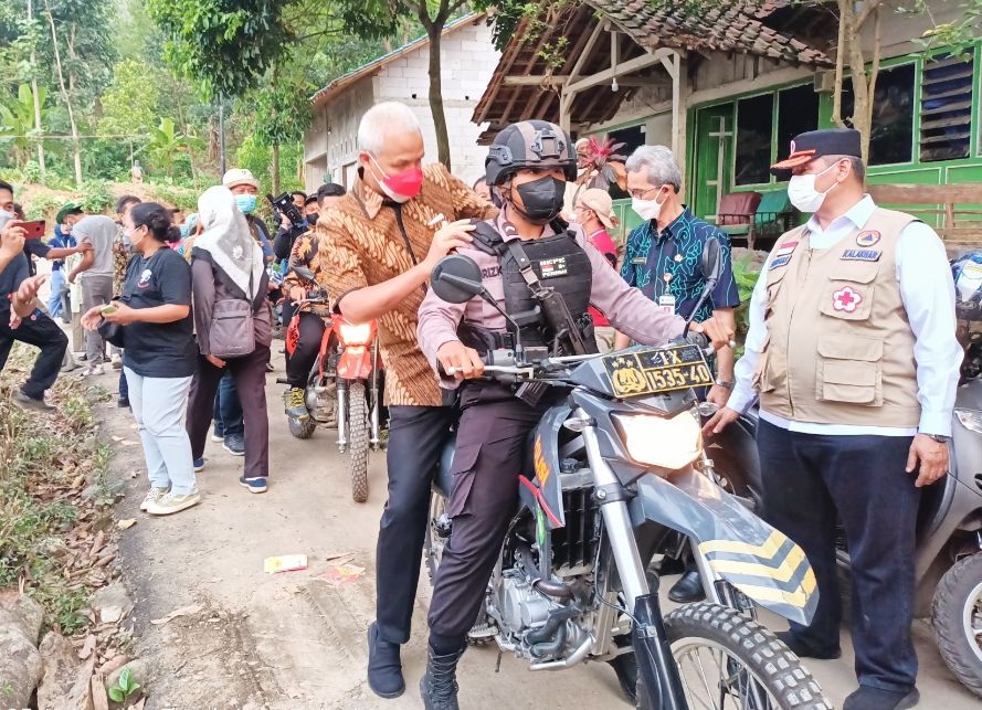 Ganjar Pranowo membonceng motor salah satu petugas Polres Tegal saat meninjau lokasi terparah bencana tanah bergerak di Desa Dermasuci