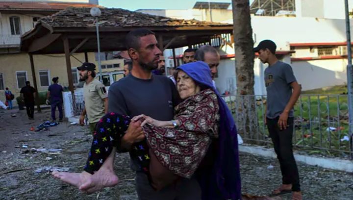 Seorang pria Palestina menggendong seorang wanita tua sesaat setelah serangan udara negara zionis ke RS Al-Ahli DI Kota Gaza.
