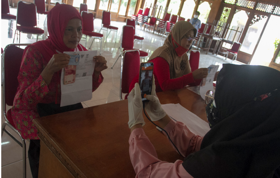 Petugas PT Pos Indonesia (Persero) memotret data warga penerima Bantuan Sosial Tunai (BST) saat pembagian di Kantor Kelurahan Manahan, Solo, Jawa Tengah, Selasa (26/1/2021). Pada tahun 2021, pemerintah juga menyalurkan BLT Dana Desa Rp300.000.