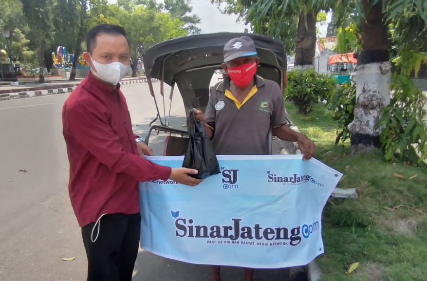 Pimred SinarJateng.com Intan Hidayat sedang membagikan nasi bungkus, masker dan hand sanitizer kepada tukang becak