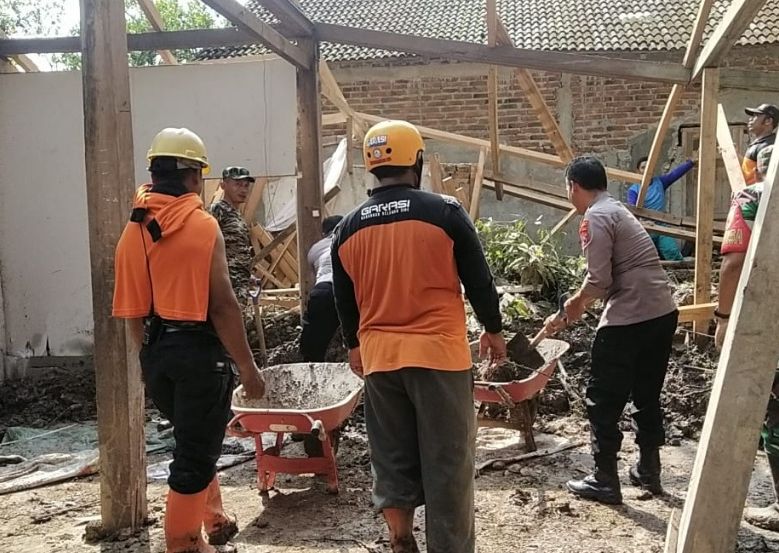 Warga Desa Pocol Kecamatan Sine Kabupaten Ngawi dibantu BPBD, Polsek dan Koramil membersihkan rumah yang tertimbun longsor