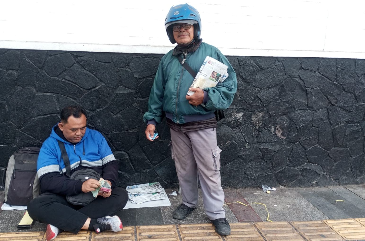 Taofiq Zulkarnaen Alkaf (48) dan Subagio (66) sedang bertransaksi jual-beli koran. Subagio merupakan loper sedangkan Taofiq merupakan agen koran di Jalan Naripan, Bandung, Jawa Barat, Sabtu, 9 Maret 2024.