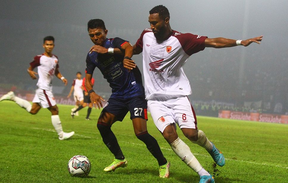 Pemain PSM Makassar kostum putih, Yuran Fernandes sedang berebut bola dengan pemain lawan. 