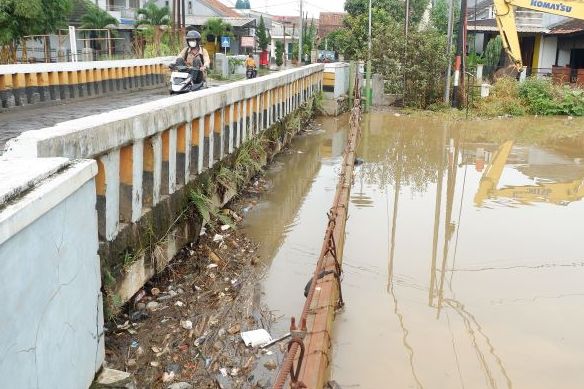 Pengguna sepeda motor menaikan kaki saat melintasi Sungai Cikeruh di Desa Tegalluar Kecamatan Bojongsoang Kabupaten Bandung yang meluap Kamis 23 Maret 2023.