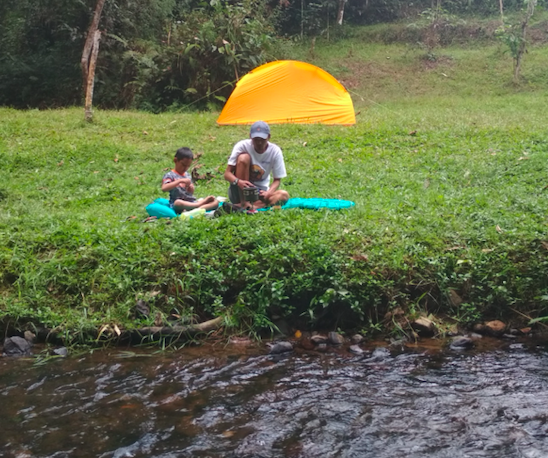 Seorang ayah dan anak santai di Camping Ground Citalahab, Desa Wisata Malasari, Nanggung, Kabupaten Bogor
