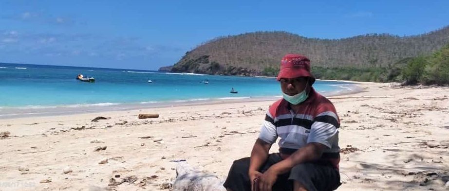 Konstantinus Kia sedang duduk di pesisir pantai Pasir Putih Watan Lolo.