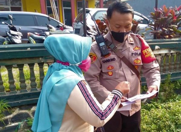 Seorang ibu menunjukan kartu vaksin kepada Kapolsek Cikancung AKP Carsono, yang turun langsung mempimpin Operasi Yustisi Penegakan Prokes di Jalan Tanjunglaya Kecamatan Cikancung Kabupaten Bandung, Kamis 6 Januari 2022.  