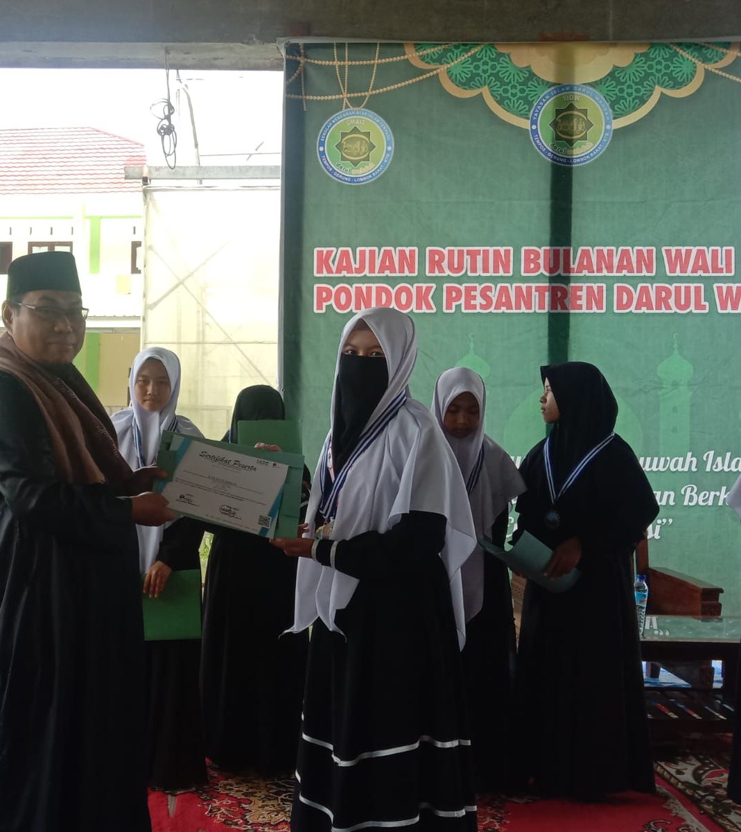potret proses pemberian medali dan sertifikat oleh Mudirul Ma'had SIT Darul Wahdah kepad siswi berprestasi tingkat Nasional