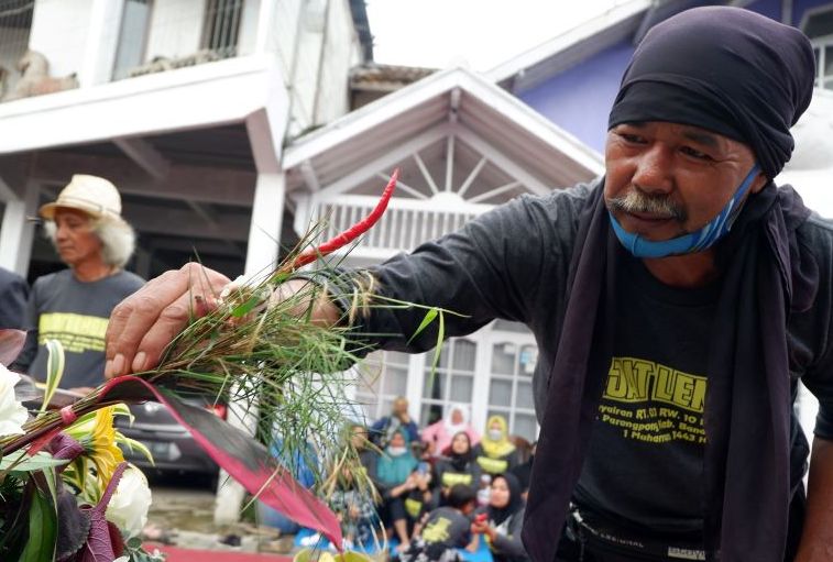Sesepuh Kampung Panyairan Desa Cihideung Kecamatan Parongpong Bandung Barat, memasangkan tolak bala di nasi tumpeng utama pada tradisi Hajat Lembur,Selasa 10 Agustus 2021.