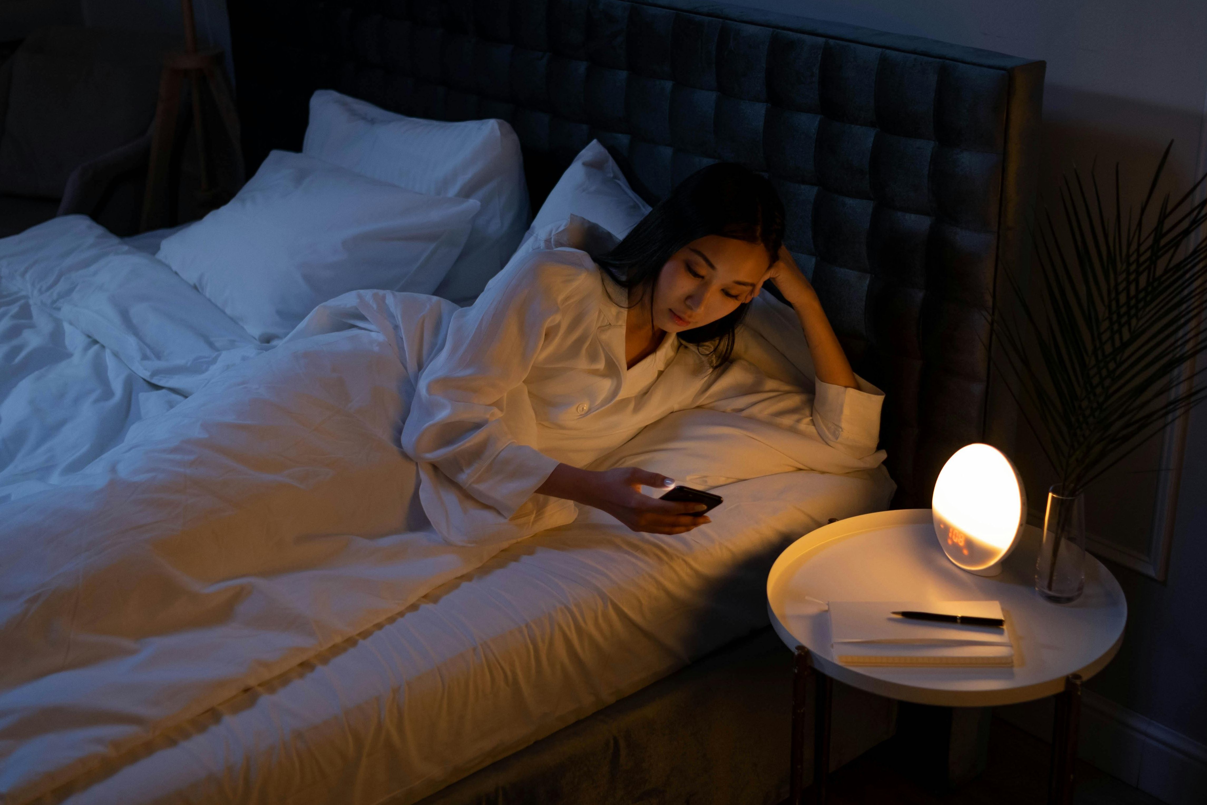 Ilustrasi seorang perempuan yang alami gangguan tidur dan asik dengan ponsel atau gawainya.
