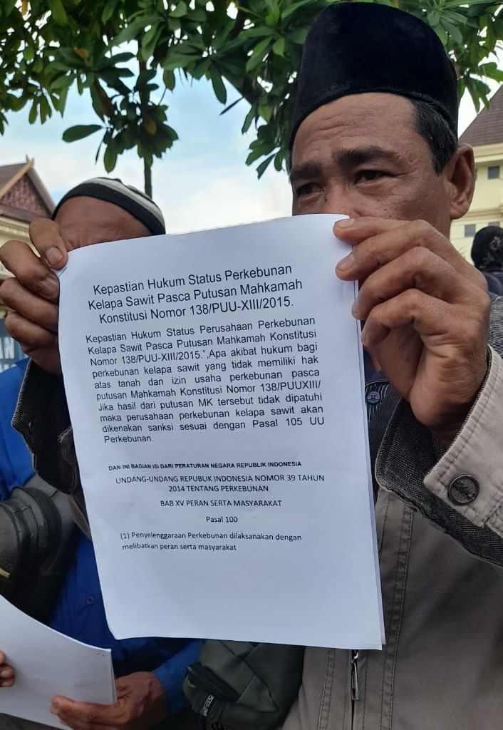 Seorang petani Serikat Tani Kumpeh membentangkan selambar kertas yang berisi ketentuan pidana bagi perusahaan perkebunan kelapa sawit yang tidak memiliki HGU.