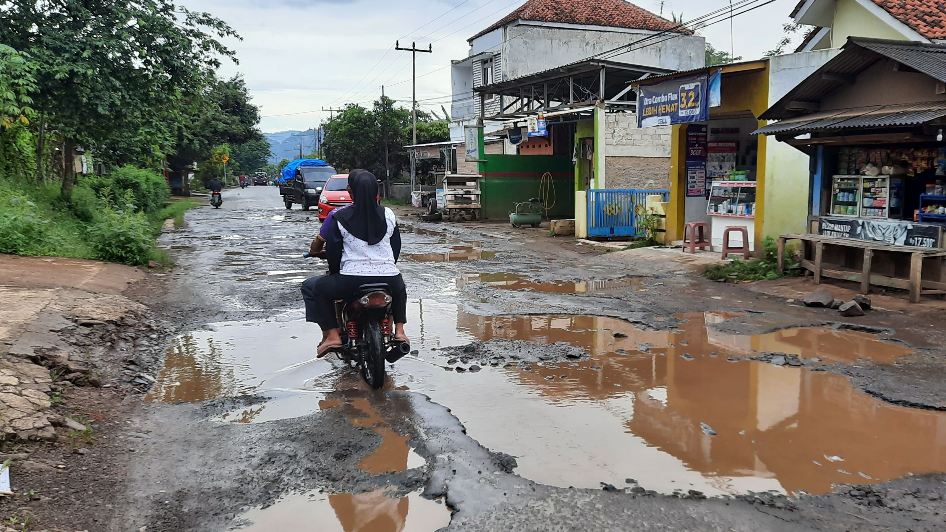 Warga melintasi jalan provinsi penghubung Cikalong-Rajamandala yang rusak di Kampung Ciwaru, Desa Bojongmekar, Kecamatan Cipeundeuy, Kabupaten Bandung Barat, Rabu 4 Januari 2023.