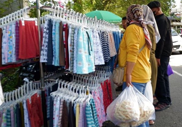 Seorang ibu tengah membeli pakaian impor yang banyak didatangkan dari Cina  di pasar mingguan Taman Cihapit Kota Bandung.  Regulasi larangan thrifting barang impor barang atau pakaian bekas akan sangat berpengaruh pada pedangan pakaian. 
