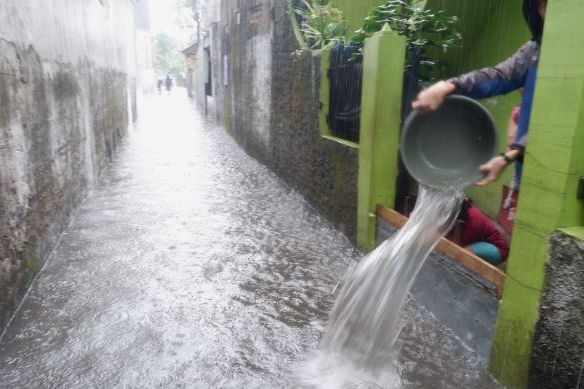 Warga membuang air yang masuk ke dalam rumah  di Jalan Sindangsari  Kelurahan Antapani Wetan Kecamatan Antapani Kota  Bandung.