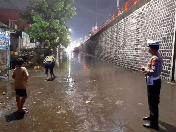 Petugas kepolisian berjaga dibawah flyover Cimahi yang terendam banjir akibat luapan Sungai Ciwarga dan Ciputri, Selasa 5 Desember 2023 malam.