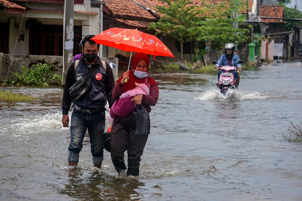 Warga melewati jalan terdampak banjir di Pekalongan, Jawa Tengah, Senin (15/2/2021). Berdasarkan dat/Harviyan Perdana Putra/ANTARA FOTO