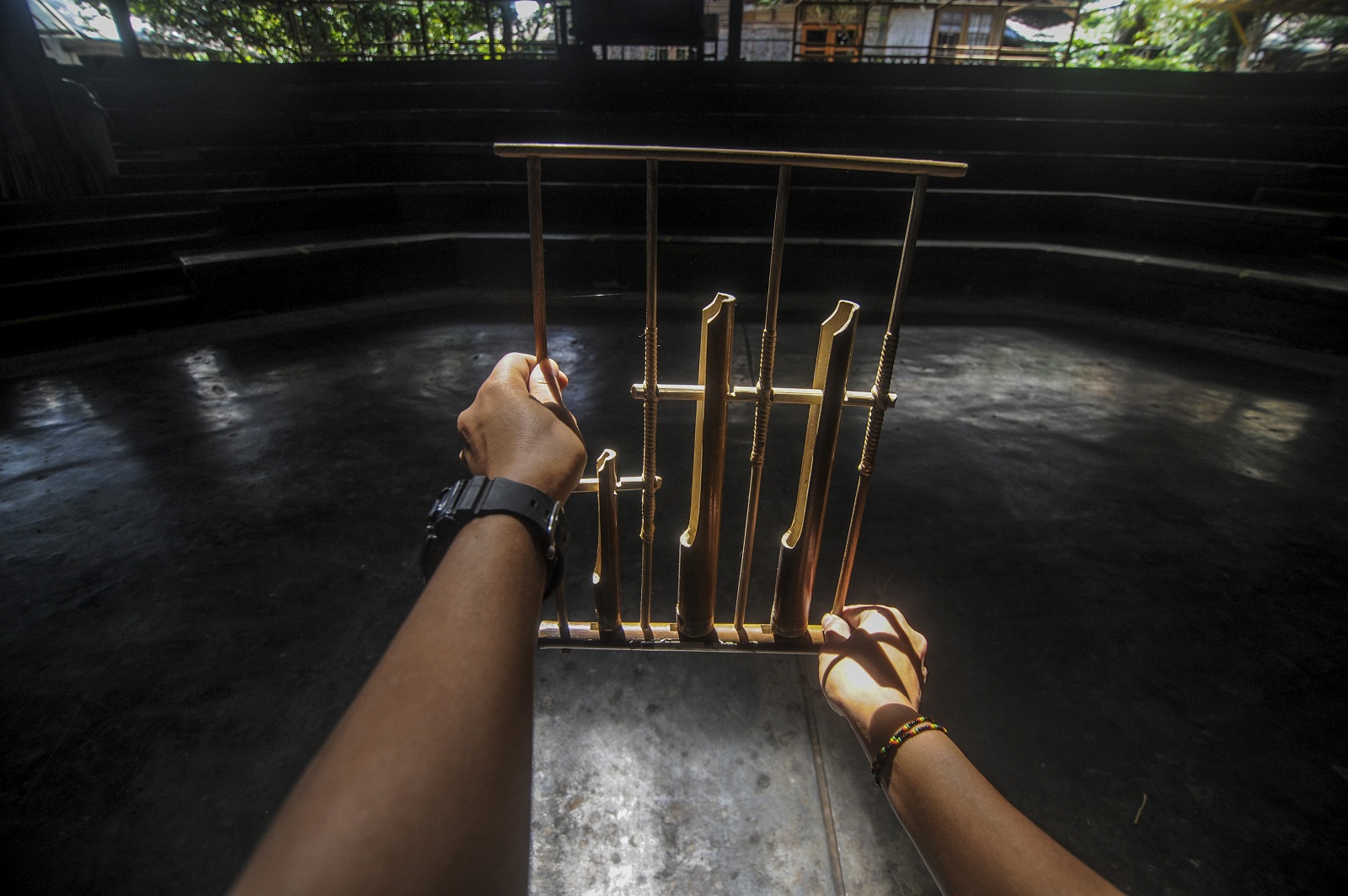 Seorang instruktur memegang angklung di aula pementasan yang kosong di Saung Angklung Udjo.