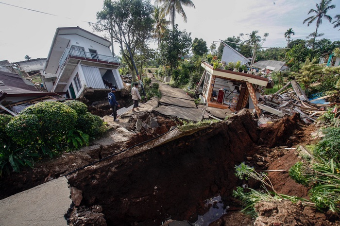 Warga melintas di dekat reruntuhan bangunan akibat gempa di Cugenang. /ANTARA FOTO/Yulius Satria Wijaya.